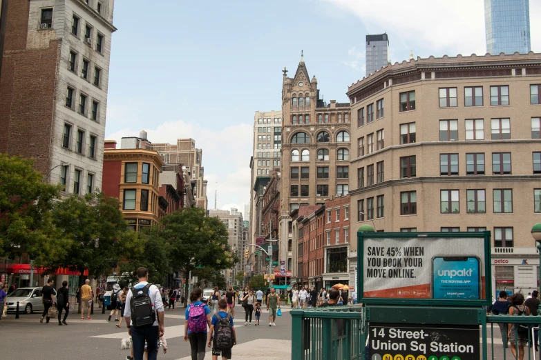 many people walk down a city street with buildings in the background