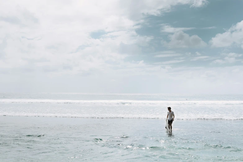 the man is standing alone in the water on a sunny day