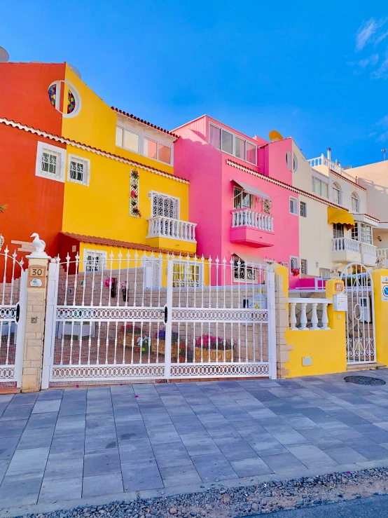 four colorful homes on both sides of a paved driveway