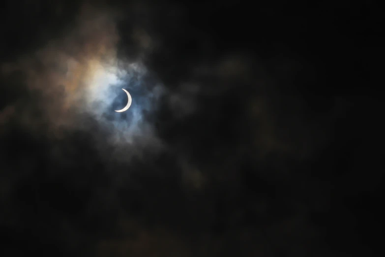 a small moon is shining through the clouds