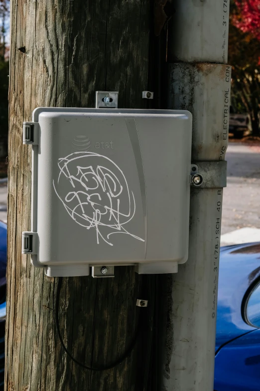 a graffittied box sits on a tree on a city street