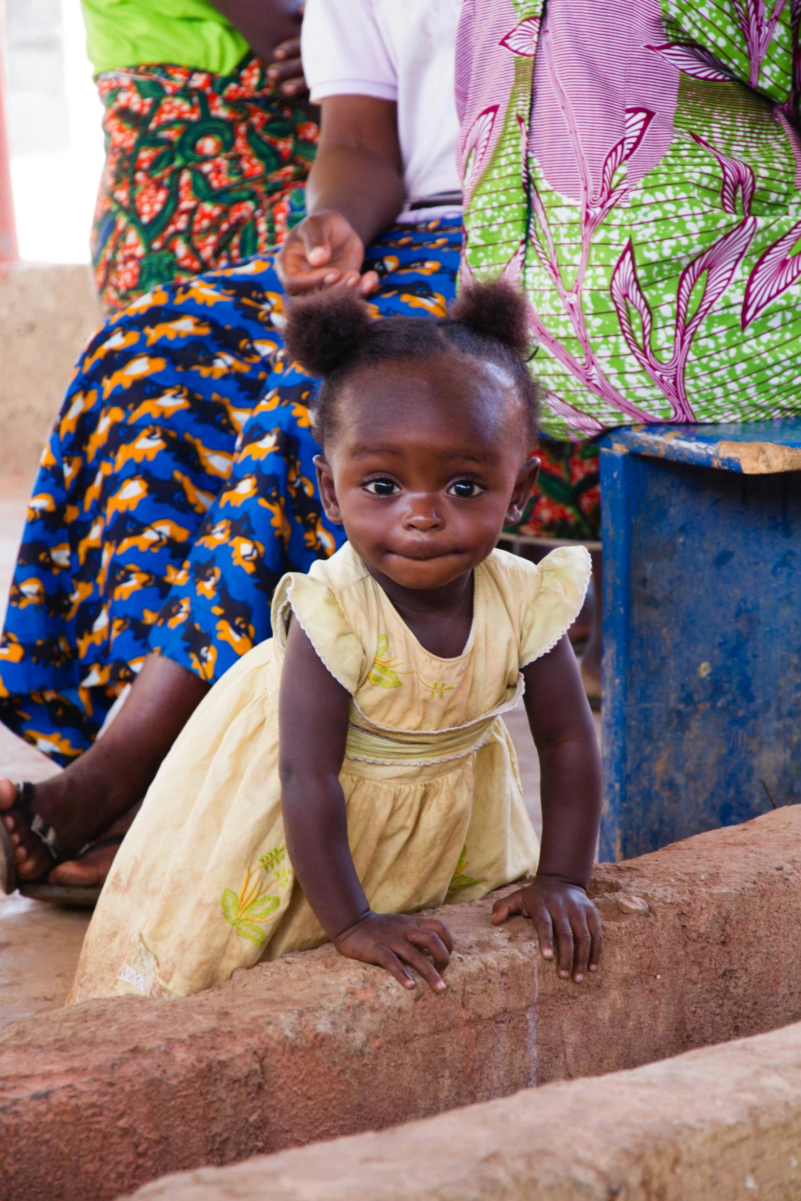 a small child wearing a dress next to some women