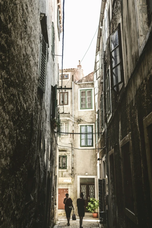 the two people are walking down the alley way