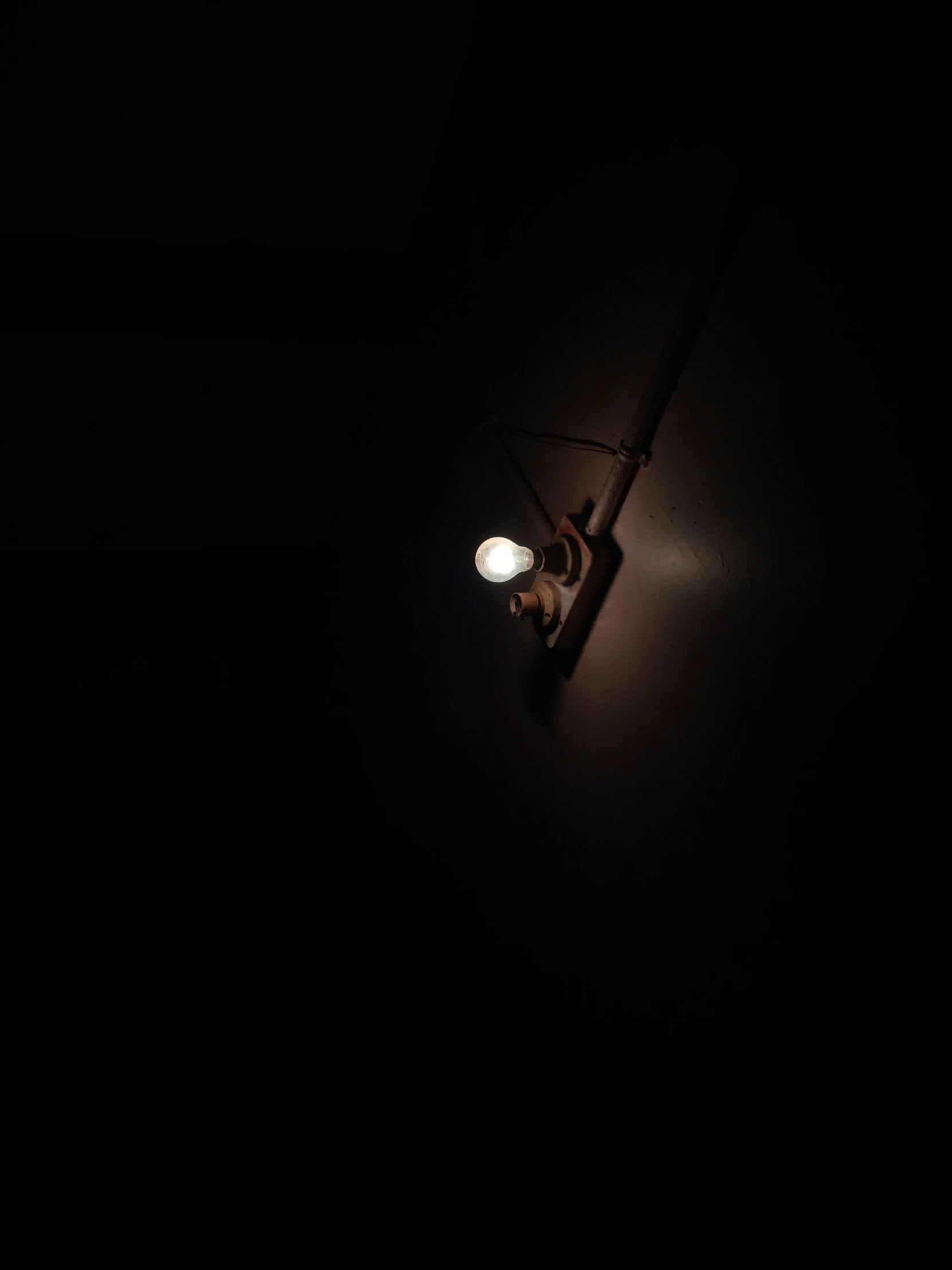a black lamp shining on the dark wall
