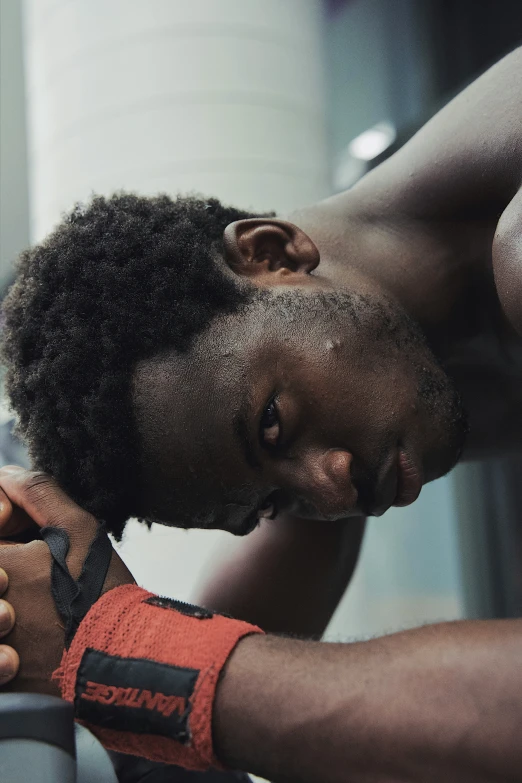 a black man looks down from a gym machine