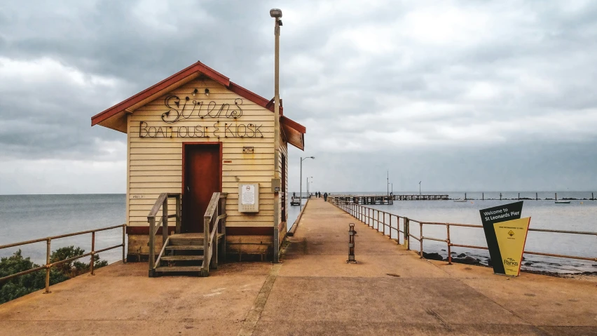 a lifeguard hut sits on the shore with stairs and signs