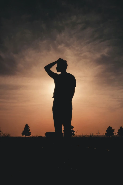 a person standing alone in the sun with a hand on his face