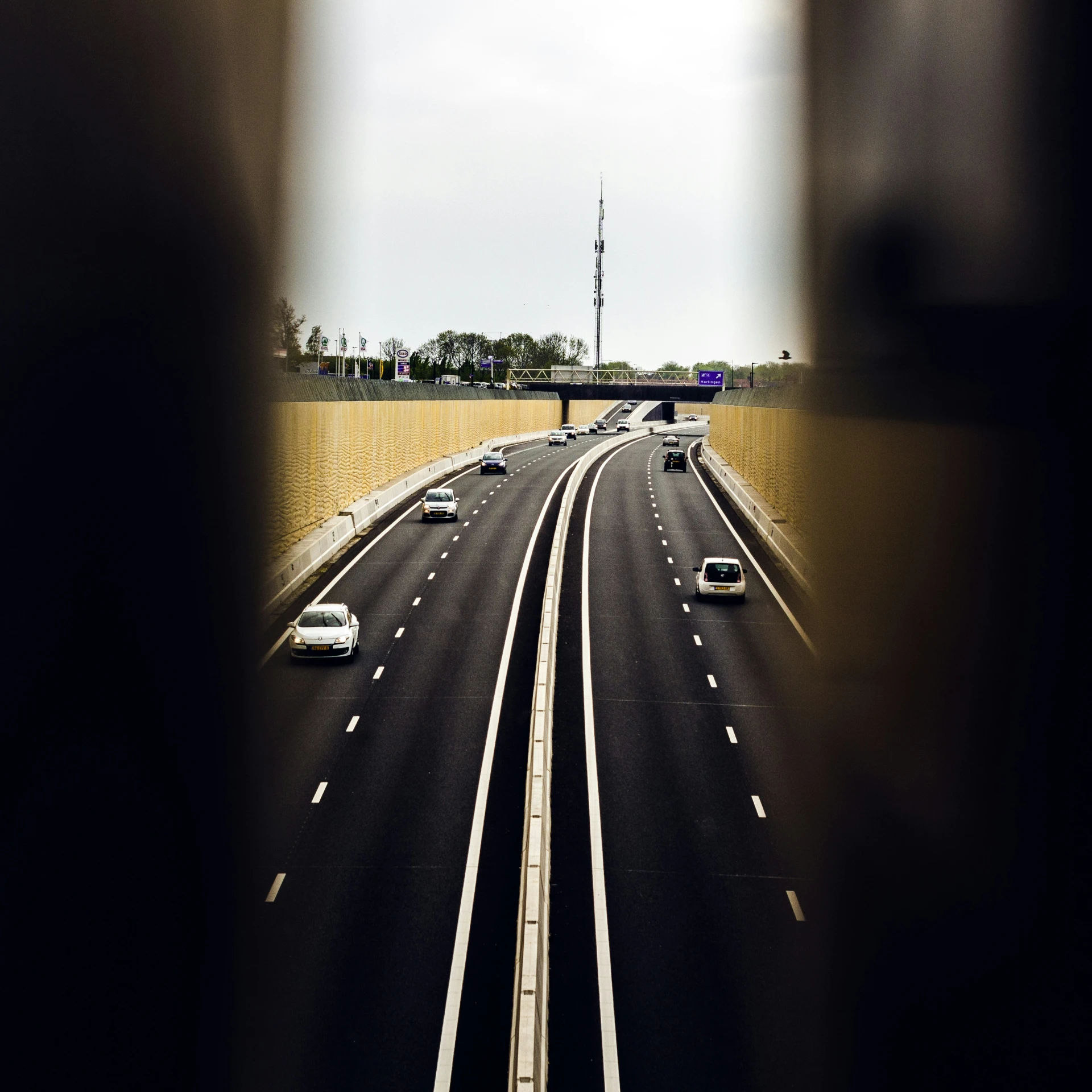 a picture of highway with vehicles passing through a tunnel