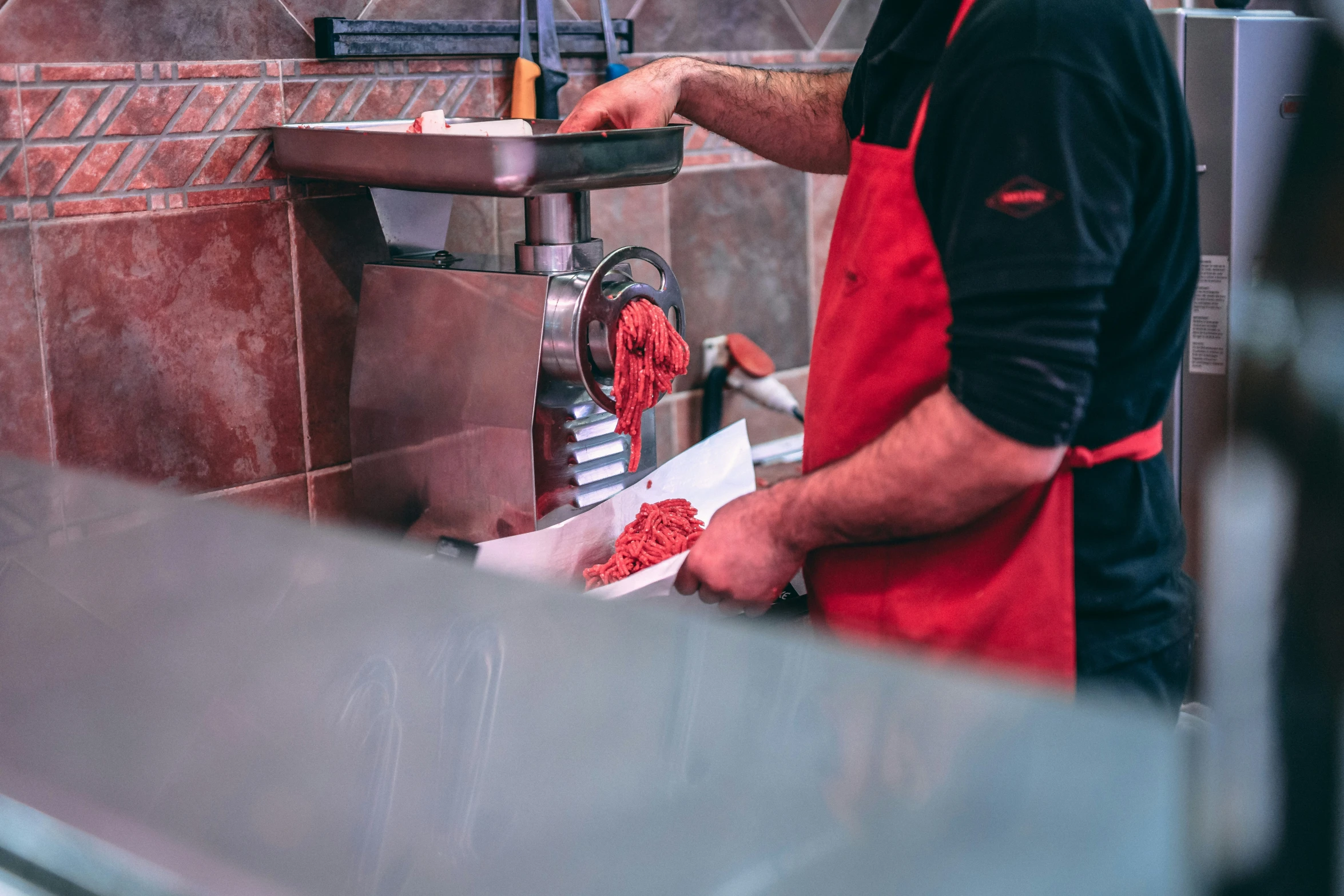 a man in a red apron holding scissors and  meat