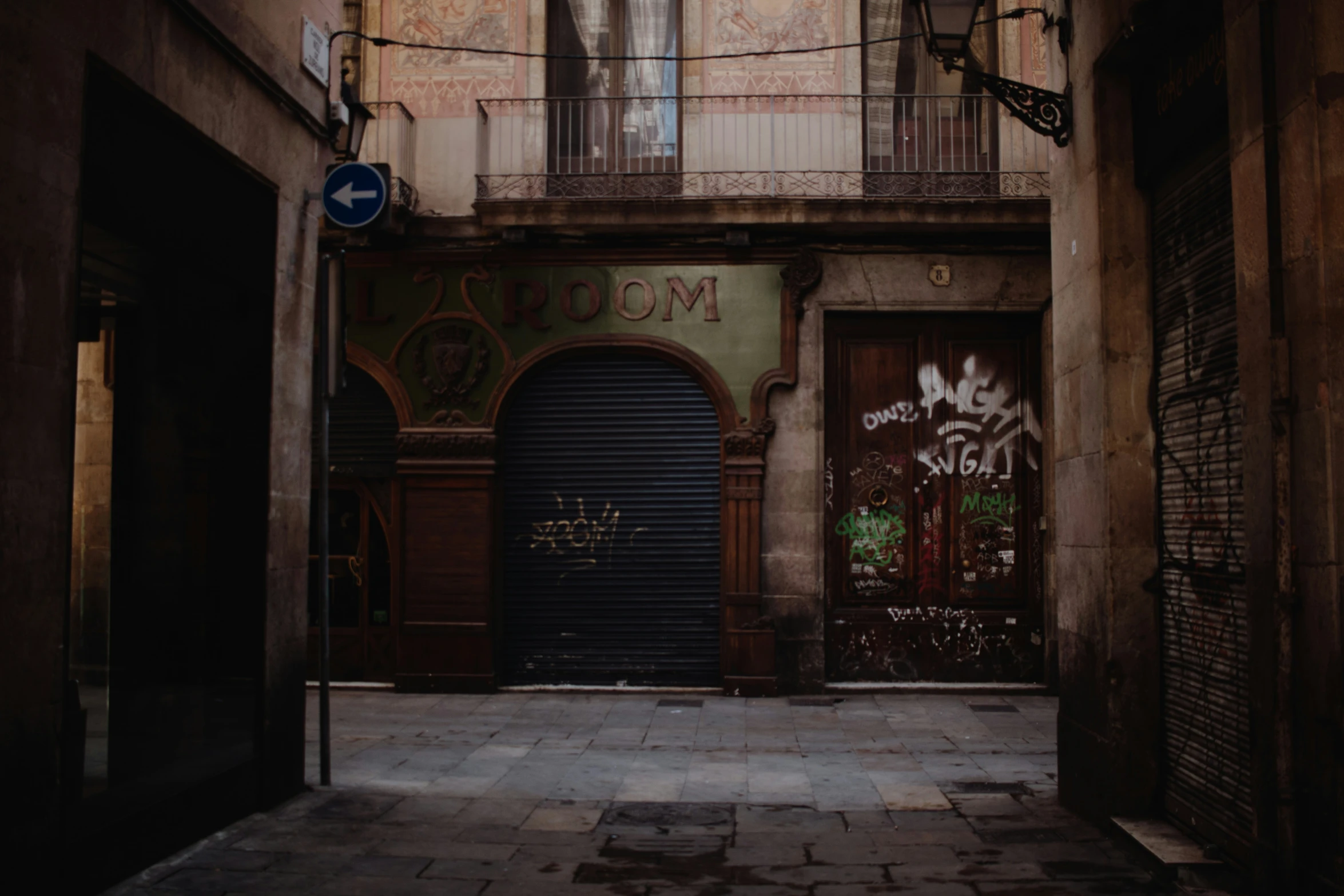 an alleyway with brown door and blue street sign