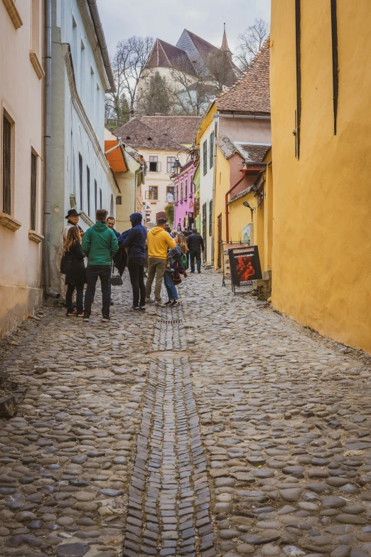 people walking down a cobblestone street in a city