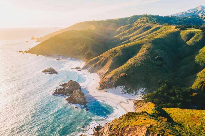 a mountain side next to the ocean with an island in the middle