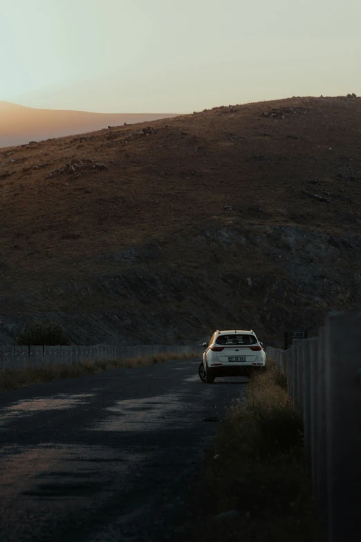 a car is parked next to a fence on the road