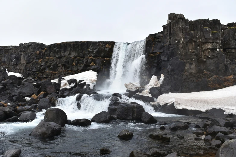 waterfall with rocks, and snow in front