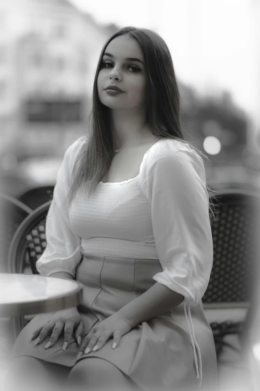 a girl wearing a dress sitting outside next to a table