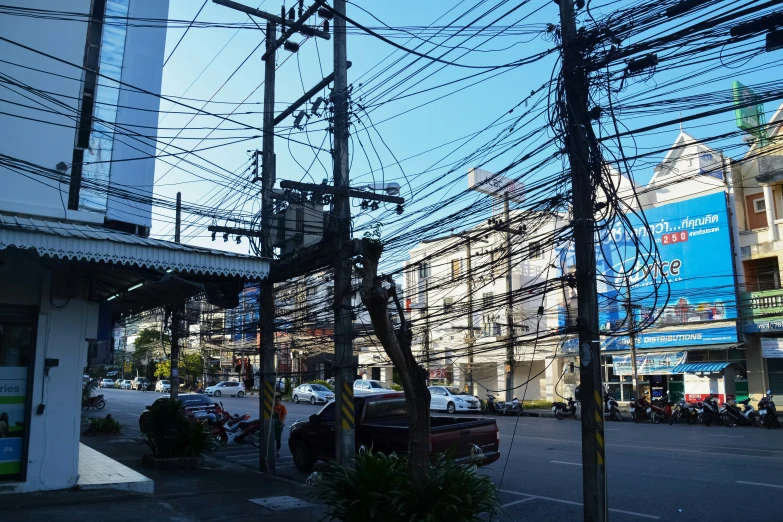 an intersection with electric wires on both sides and vehicles parked at the curb