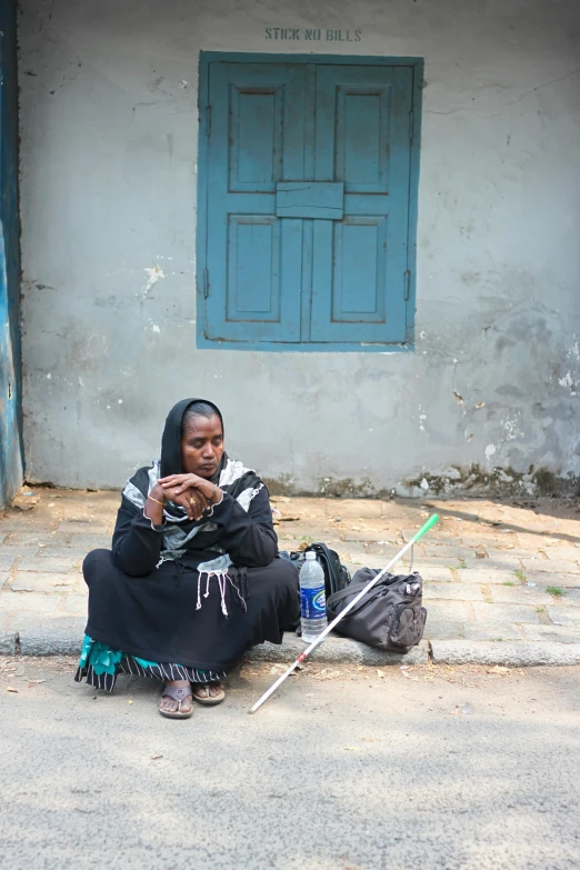 a women sits on the curb while listening to a cell phone