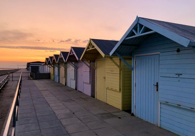 rows of beach huts on the beach next to the ocean