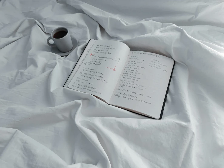 a book on a sheet with an empty cup in the middle