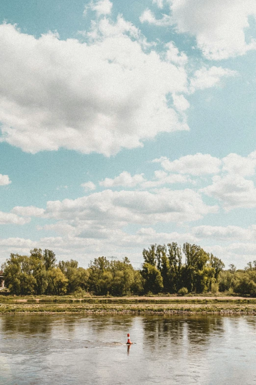 a person is standing alone in the water with an airplane in the sky