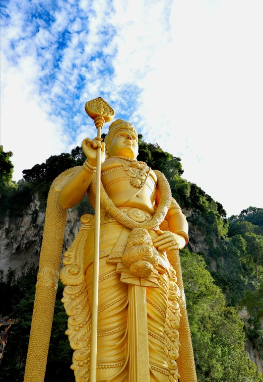 a statue of an indian god stands in front of a scenic mountain view