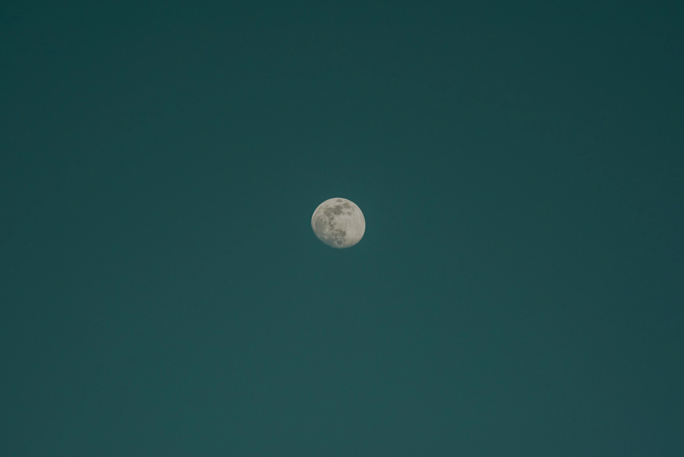 an image of a very distant moon over some mountains