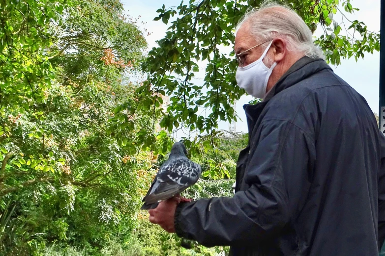 a man is wearing a mask while holding a bird