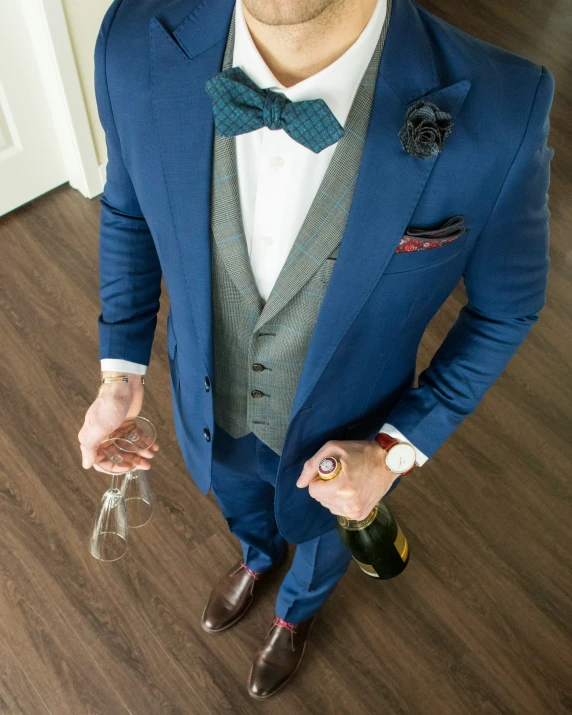 the man is holding two bottles and wearing a suit