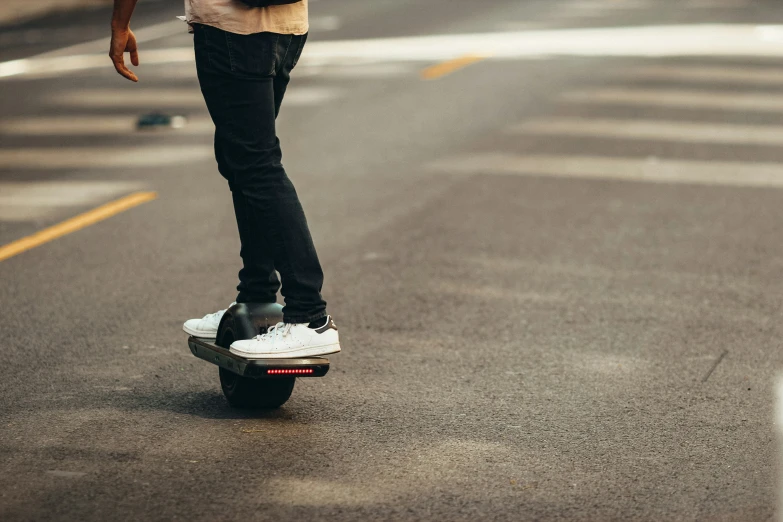 young male riding skateboard on street with cars in background