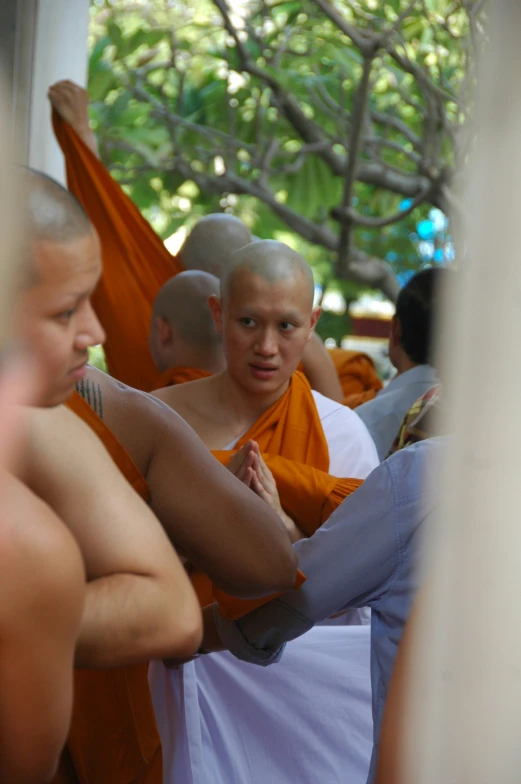 a monk putting on another person's shirt