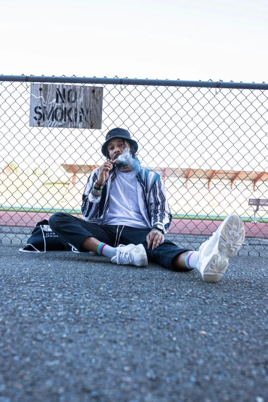 a person sits on the ground by a fence