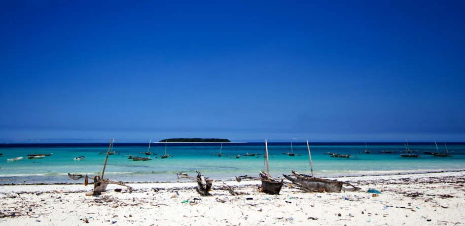 a body of water near several small boats on a sandy beach