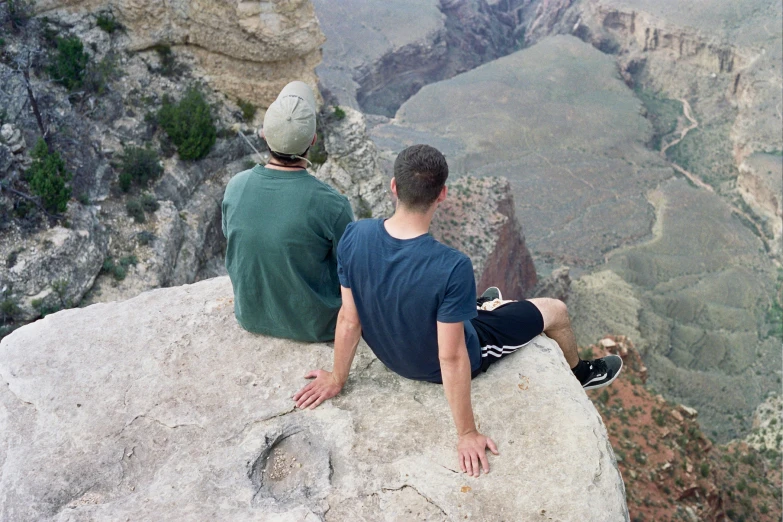 two people sitting on top of a mountain looking into the sky