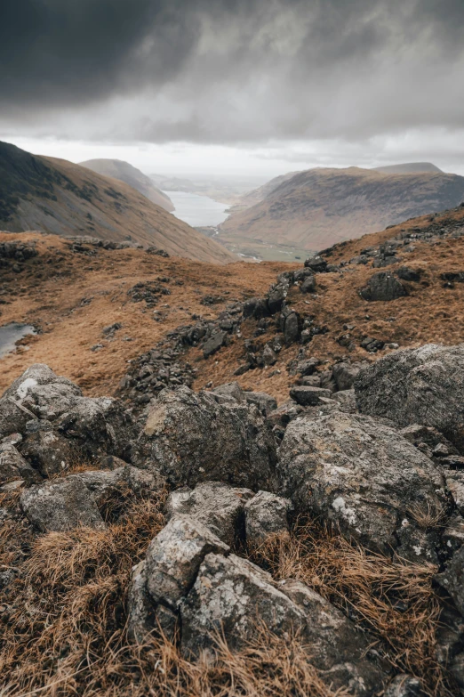 a rocky outcropping in an open field with mountains in the background