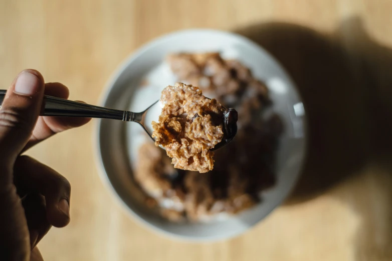 a spoon holding a scoop of oatmeal on a wooden table