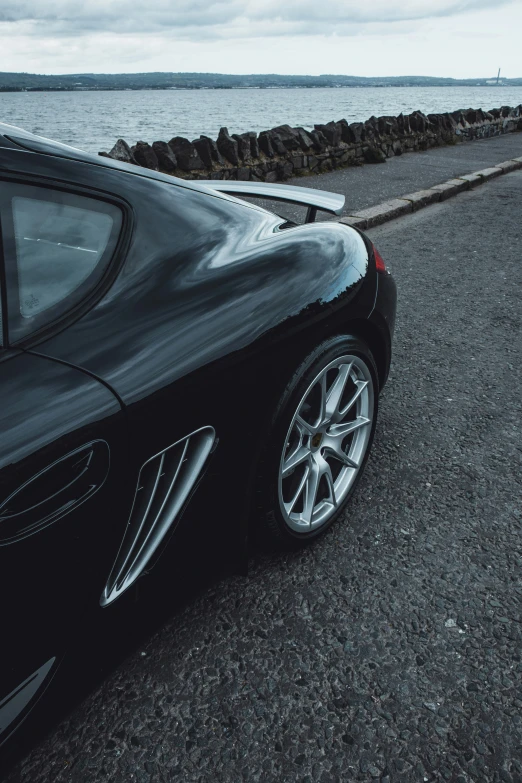 a black sports car parked on the beach near a shoreline