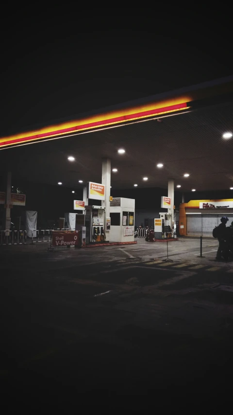 a gas station with a neon sign above the gas pumps