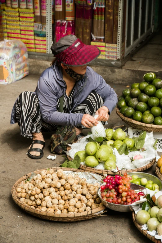 woman sitting on the ground surrounded by fruits