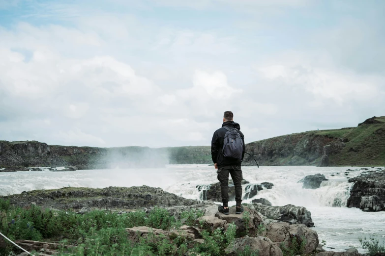 a man standing on rocks looking over water