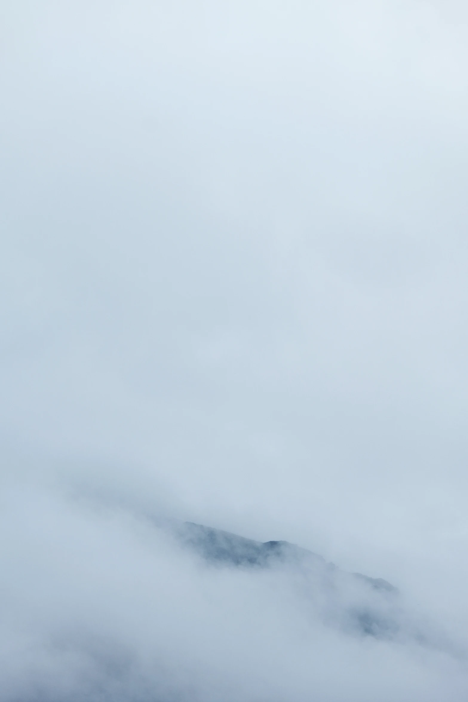 a plane is flying in the clouds as seen from a hill