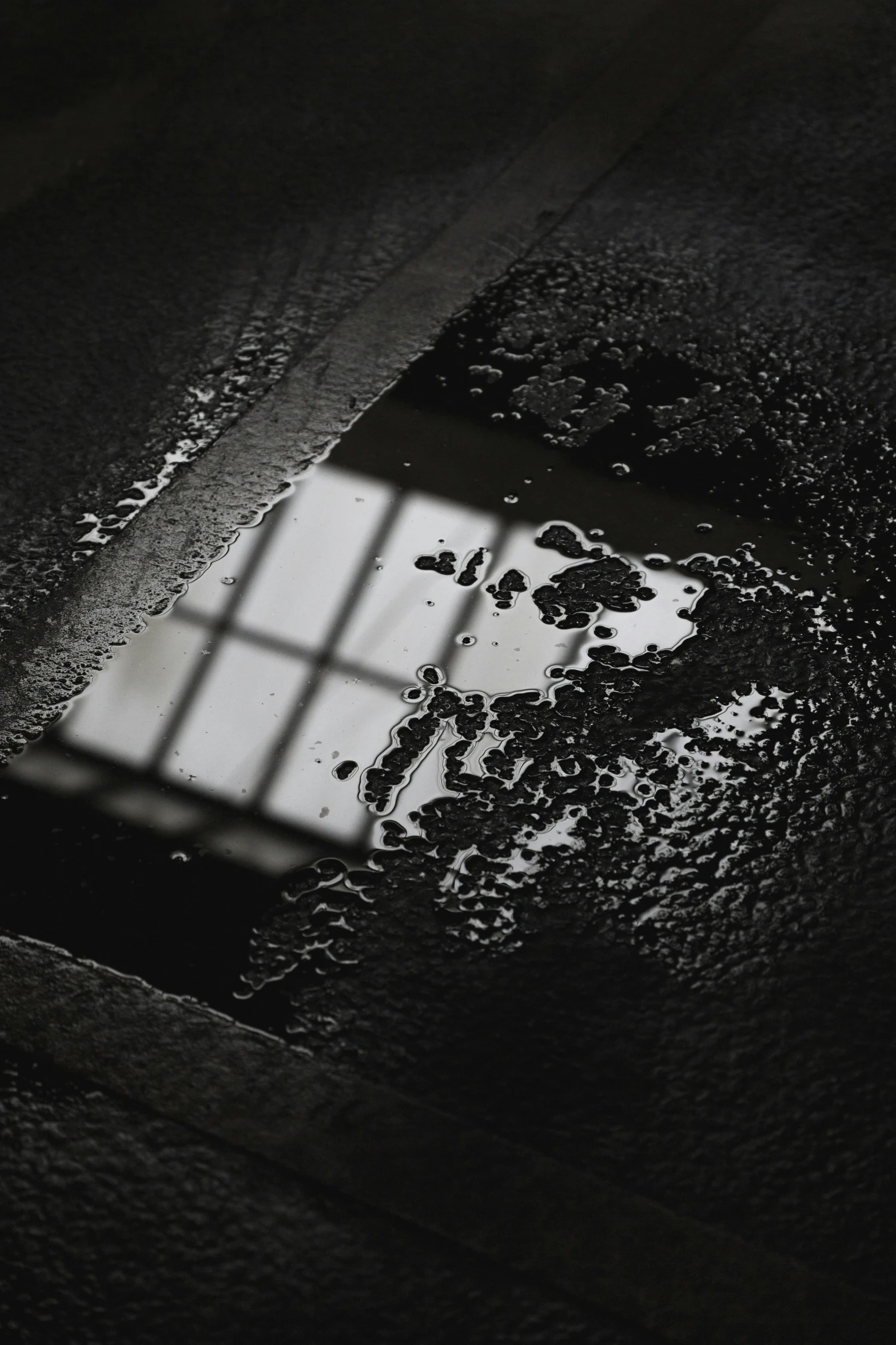 a window is reflected in the ground and the tile has been wet