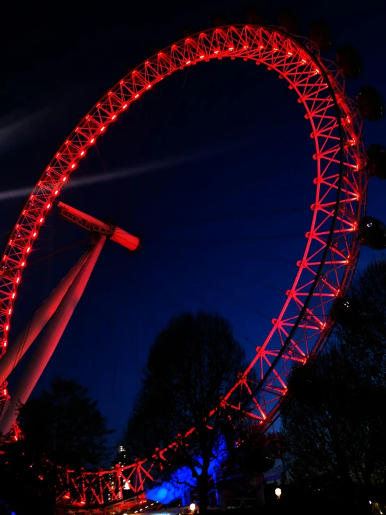 the ferris wheel is lit up red at night