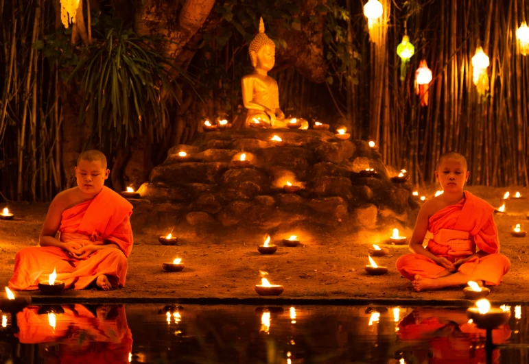 monks are sitting in a pond surrounded by candles