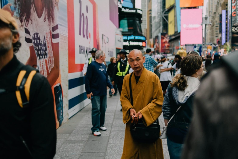 a man in yellow is standing on a sidewalk with people