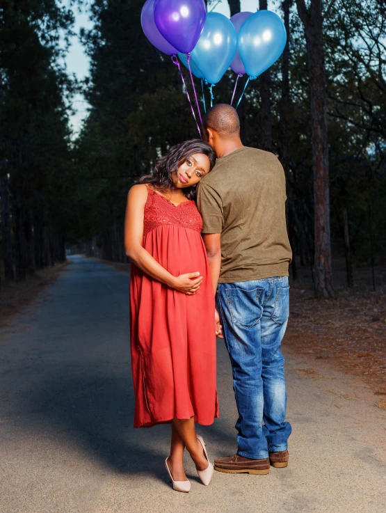 a man and woman stand in the road while holding balloons