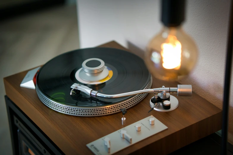 a turntable and light bulb sit on a small wooden table