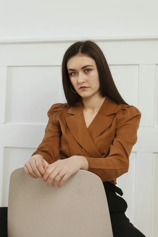 a woman in a brown jacket sitting on a brown couch