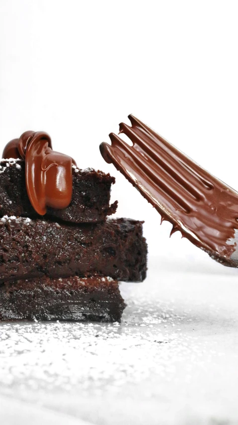 a piece of chocolate cake being dipped with brown er