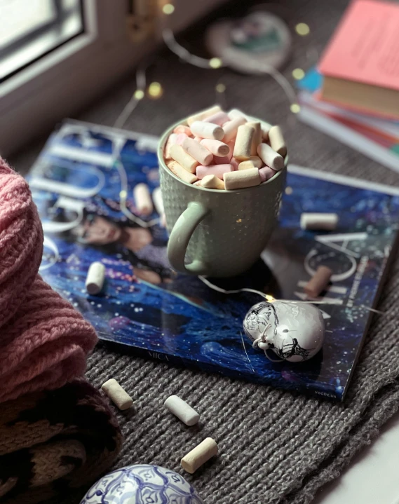 a mug filled with marshmallows sits on top of the table