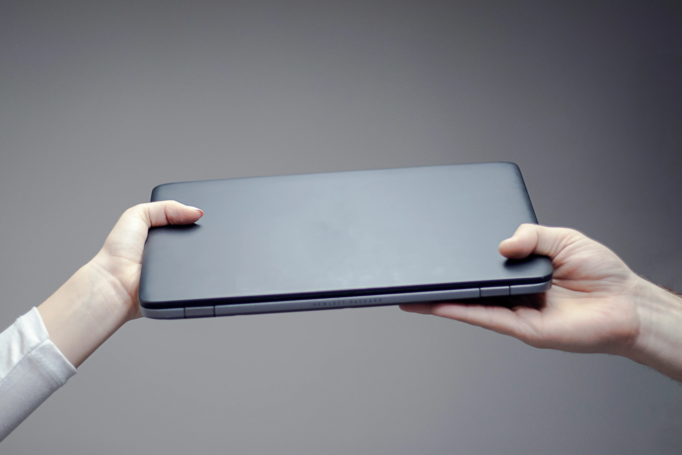 a person holding the back of a black surface laptop